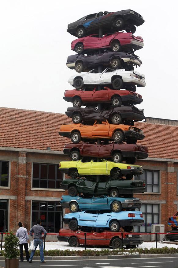 Visitors look at an art form made by piles of colorful scraped cars, entitled
