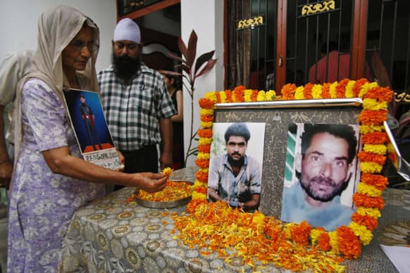 Satya Devi, mother of Gopal Das, who had gone missing while fighting for Indian side during Indo-Pakistani war, offers flowers to portraits of Sarabjit Singh and Chamel Singh during a press conference by Missing Defense Personnel Relatives Association in Jammu.