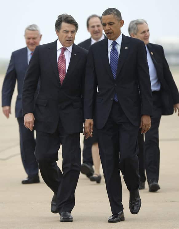 President Barack Obama, right, talks with Texas Gov. Rick Perry, left, as the walk on the tarmac during his arrival on Air Force One at Austin-Bergstrom International Airport.