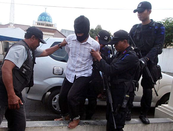 Police officers lead a suspected militant arrested during a raid in the town of Kebumen upon arrival in Semarang, Central Java, Indonesia.