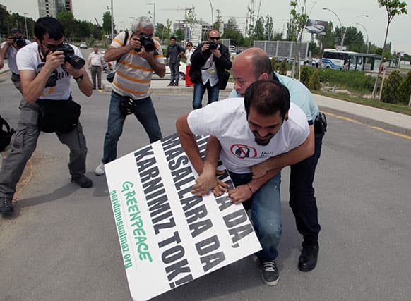 A security agent tries to detain a member of the environmental group Greenpeace who is holding a banner that reads