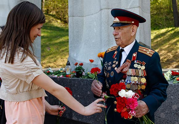 Aleksey Asolski, a 91 -year-old veteran of World War II receives flowers from a young woman at the Antakalnis memorial during Victory Day celebrations in Vilnius, Lithuania.