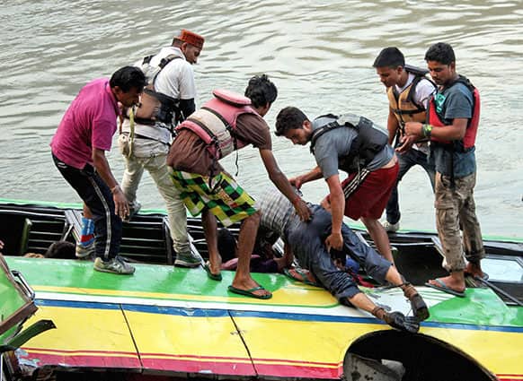 Rescuers take out a body from a bus that plunged into the Beas River near Kullu. More than 30 people were killed when an overloaded bus plunged into the river on the Kullu-Mandi national highway Wednesday, according to a news agency.