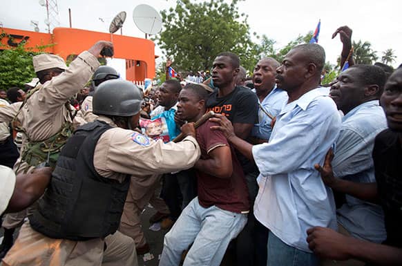 Police use batons to push back supporters of Haiti`s former President Jean-Bertrand Aristide as Aristide leaves the courthouse in Port-au-Prince, Haiti.