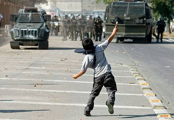 A youth throws stones at police during a student protest demanding free education in Santiago, Chile.