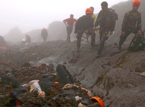 Soldiers and rescuers look at a body, believed to be that of a German national, under the rubble near the crater of Mayon volcano in Albay province about 450 kilometers (285 Miles) southeast of Manila, Philippines.