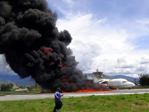 Smoke billows from a British-made BAe 146 cargo plane that caught fire while being unloaded on the tarmac at the airport in Wamena, Papua province, Indonesia. An official said that the plane caught fire after a drum of oil fell from the aircraft and somehow sparked the fire.