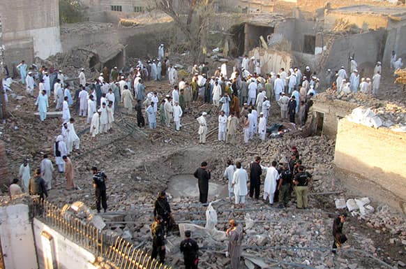 People gather at the site of a bombing in Bannu, Pakistan. Early Wednesday, a suicide bomber detonated a car packed with explosives outside a police station in the city of Bannu in Khyber Pakhtunkhwa, killing a person and wounding others, police officer Rafiq Khan said.