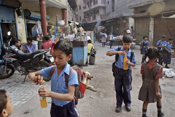 Schoolchildren make cold drinks as they walk to school in New Delhi. Northern and eastern plains continued to reel under the searing heat wave, with the mercury rising above 41 degrees Celsius in Delhi.