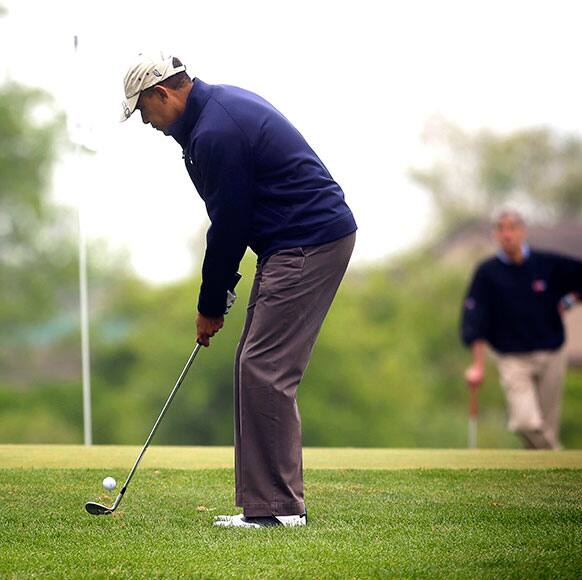 President Barack Obama, left, with Sen. Mark Udall, D-Colo., right, chips on the first hole of the golf course at Andrews Air Force Base, Md.