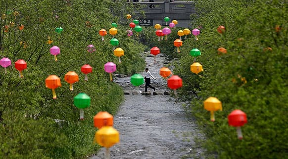 A man crosses a stream under the lanterns hanging for the upcoming Buddha`s birthday on May 17, in Seoul, South Korea.
