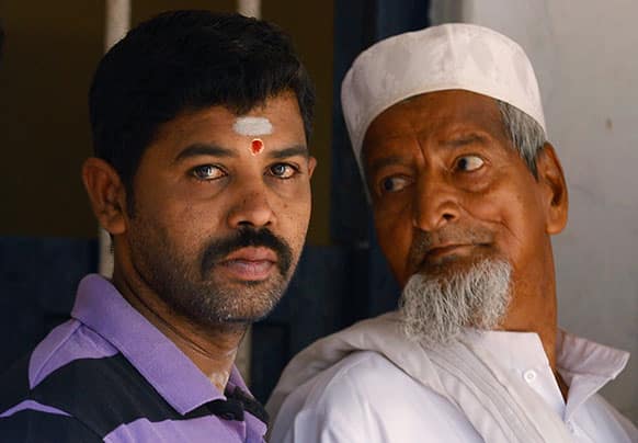 An Indian Muslim, right, stares at a Hindu man as they wait outside a polling station to caste their votes in Bangalore.