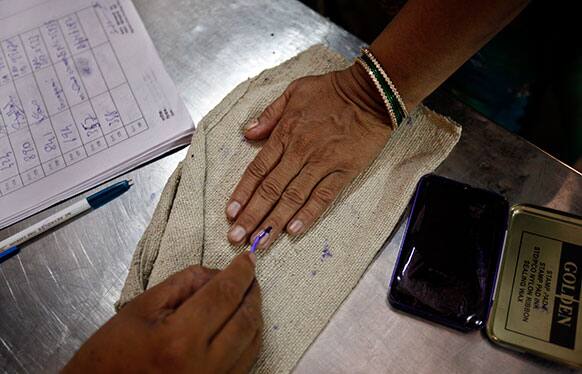 An Indian polling officer applies an indelible ink mark on the finger of a voter at a polling station in Bangalore.