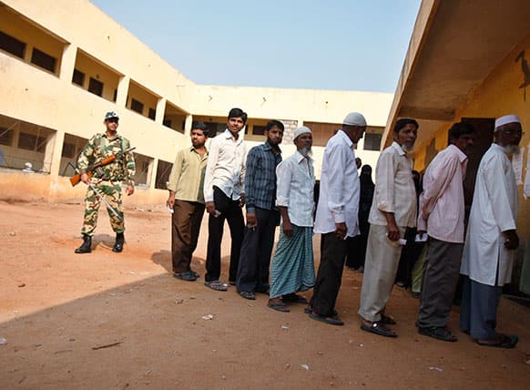 An Indian paramilitary soldier stands guard as voters line up outside a polling station to caste their votes in Bangalore.