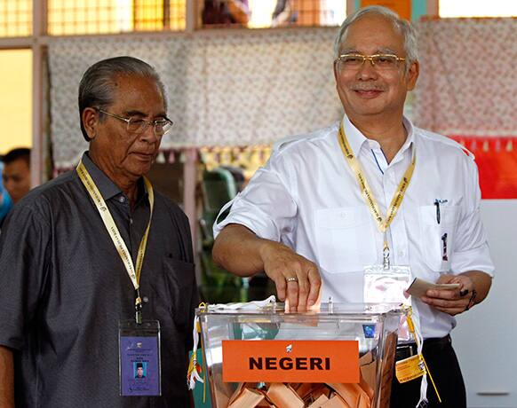 Malaysian Prime Minister Najib Razak, right, casts his ballot in the general elections at a polling station in Pekan, Pahang state, Malaysia.