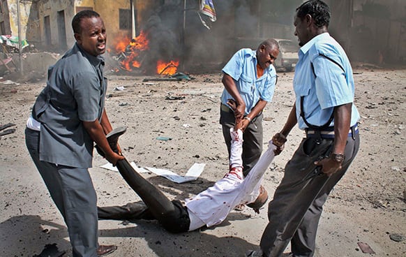 Somali security force members carry away a severely wounded man following a suicide car bomb blast in the capital Mogadishu, Somalia.