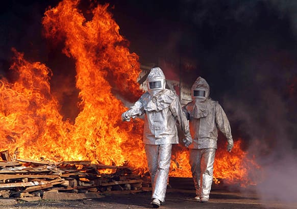Myanmar Fire Brigade members in protective suits walk through flames during an annual Myanmar Fire Brigade Day in Yangon, Myanmar.