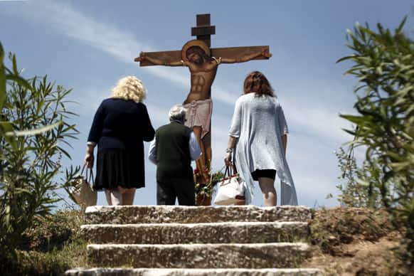 Worshippers pay homage to a giant wooden crucifix during a Good Friday reenactment of Christ being taken down from the cross, at the Pendeli Monastery, near Athens. Orthodox Christians around the world celebrate Easter on Sunday, May 5.