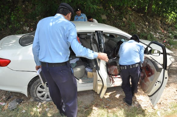 Pakistani police officers examine the car of prosecutor Chaudhry Zulfikar which was targeted by gunmen in Islamabad. Gunmen killed Pakistan`s lead prosecutor investigating the assassination of former prime minister Benazir Bhutto.