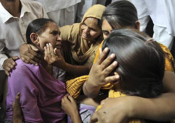 Relatives try to console Sukhpreet Kaur, wife of Sarabjit Singh, a convicted Indian who died after he was bludgeoned to death by two fellow inmates at a Pakistani prison as she and her daughters react to the news at Bhikhiwind.