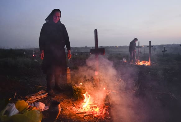 An elderly woman stands by a fire she lit near a grave in a cemetery in the village of Copaciu, southern Romania. As part of a Holy Week tradition Romanians visit, on Maundy Thursday, the graves of their loved ones, light fires and share food with community members in memory of the departed.