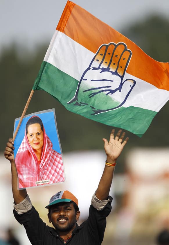 A supporter of Congress party president Sonia Gandhi holds her photograph and waves the party`s flag during a campaign rally attended by Gandhi, for the upcoming Karnataka state election in Bangalore.