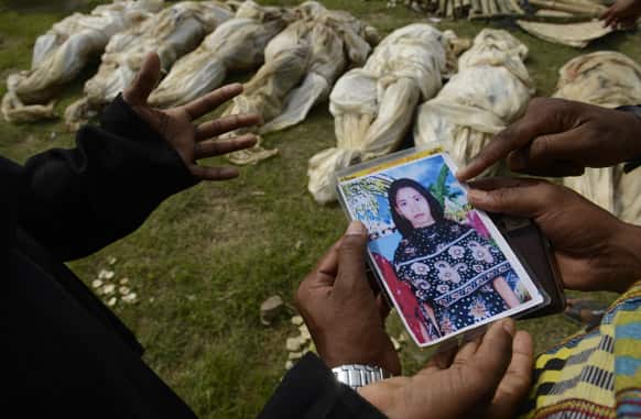 Farida shows a picture of her sister-in-law Fahima to officials as she tries to identify her among the bodies which arrived for burial in Dhaka, Bangladesh.