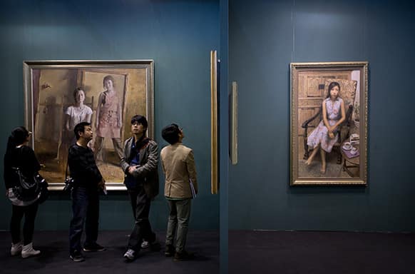 Visitors look at paintings by Phoenix Art Palace on display at the Art Beijing Exhibition, held at the Agricultural Exhibition Center in Beijing, China.
