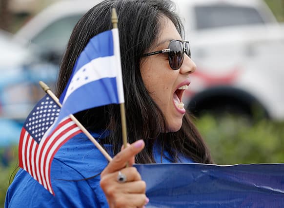 Brenda Betancourt holds American and Honduran flags as she chants during an immigration demonstration, in Doral, Fla.