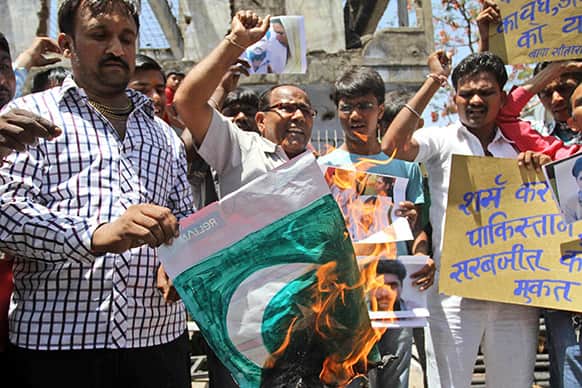 Indians shout slogans against the Pakistan government and burn their national flag during a protest against an attack on an Indian prisoner in a Lahore prison, in Ahmadabad, India.