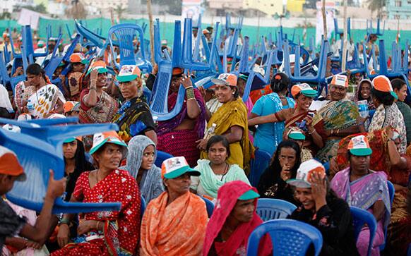Congress party supporters hold chairs to shield themselves from rain as they wait for Indian Prime Minister Manmohan Singh at a campaign rally for the upcoming Karnataka state election on the outskirts of Bangalore.