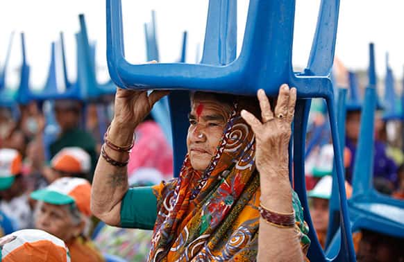 An elderly Congress party supporter holds a chair to shield herself from rain as she waits with others for Indian Prime Minister Manmohan Singh at a campaign rally for the upcoming Karnataka state election on the outskirts of Bangalore.