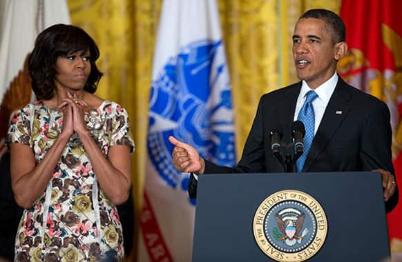 First lady Michelle Obama listens at left as President Barack Obama speaks during an event to promote hiring military veterans, in the East Room of the the White House.