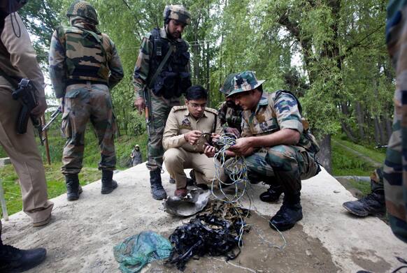 Soldiers and police officer, inspect the parts after detecting and defusing a bomb on the outskirts of Srinagar.