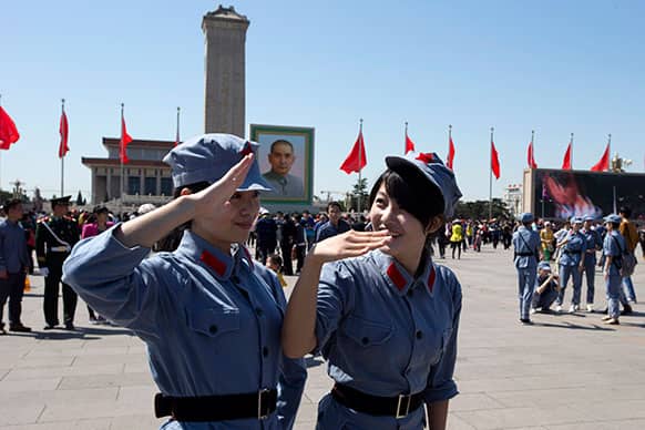 Chinese girls dressed to look like Chinese Red Army soldiers salute for a friend taking photos on Tiananmen Square on the eve of May Day in Beijing.