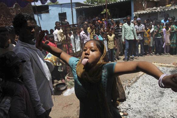 An Indian devotee reacts as she walks on burning coal as part of a ritual, after a religious procession to the temple of Hindu goddess Sheetala Mata or Muthumariamman in Ahmedabad.