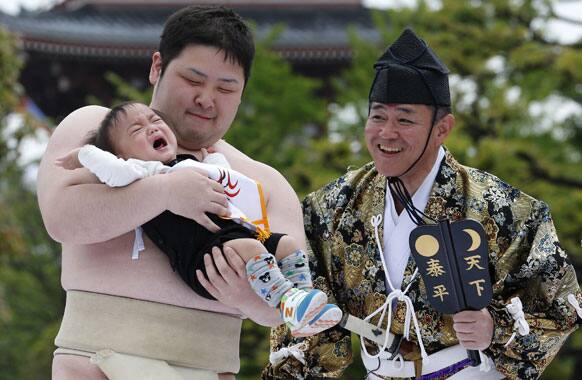An unidentified baby, held by a college sumo wrester, cries during Naki Sumo, or Crying Baby Contest, at Sensoji temple in Tokyo.