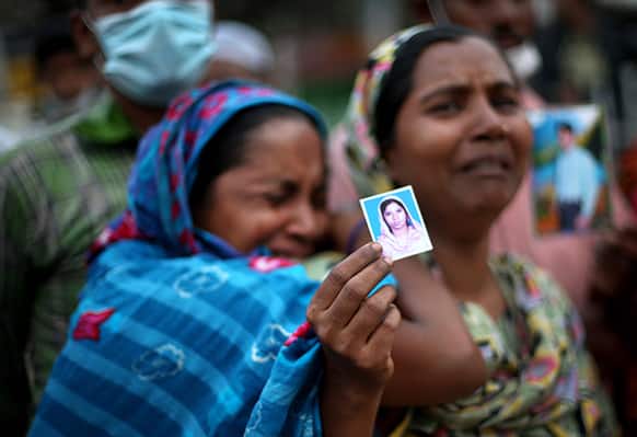 Women hold photographs of their missing relatives as they plead for help at the site where the garment factory building collapsed Wednesday in Savar, near Dhaka.