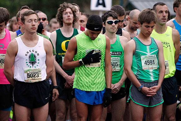 Runners take part in a moment of silence for those killed and injured during the Boston Marathon bombing before the Eugene Marathon in Eugene, Ore.