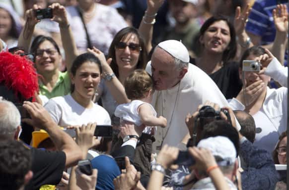 Pope Francis kisses a young child as he leaves St. Peter`s Square at the Vatican after he celebrated the holy mass and conferral of the sacrament of confirmation.