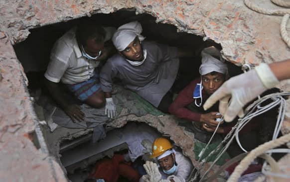 Bangladeshi rescue workers search for survivors as they are seen through a hole in the roof a building that collapsed Wednesday in Savar, near Dhaka, Bangladesh.