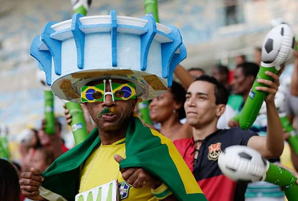 A man wears a hat in the shape of the Maracana stadium as he arrives for the inauguration of the renovated Maracana stadium in Rio de Janeiro, Brazil.