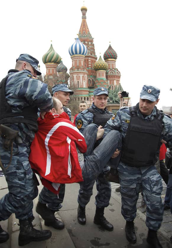 Russian police officers detain a demonstrator during an action in support of opposition activists arrested in a massive anti-president Putin rally in last May, in Red Square, with St. Basil Cathedral in the background, in Moscow.