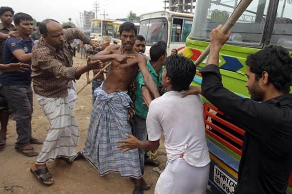 Bangladeshi garment workers beat a driver, for not stopping a bus he was driving, during a protest against the collapse of an eight-storey building that housed several garment factories and poor working conditions of the employees, in Dhaka.