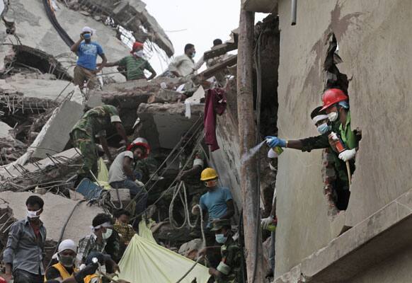 Bangladeshi spray deodorant to mask the smell of bodies Friday, April 26, 2013 amid the rubble of a building that collapsed Wednesday in Savar, near Dhaka, Bangladesh..