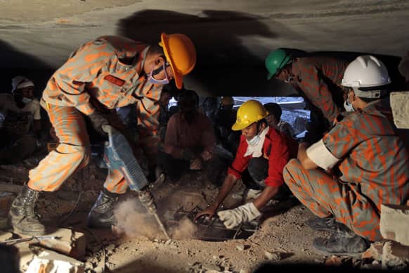 A Bangladeshi rescuer works to break through metal and concrete with a drill at the site of a building that collapsed Wednesday in Savar, near Dhaka, Bangladesh.