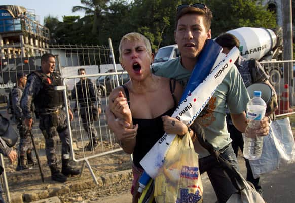 An activist reacts from the effects of tear gas fired by Brazilian police during a protest against the privatization of the Maracana stadium and planned demolition of the indigenous museum located next to the stadium, in Rio de Janeiro, Brazil.