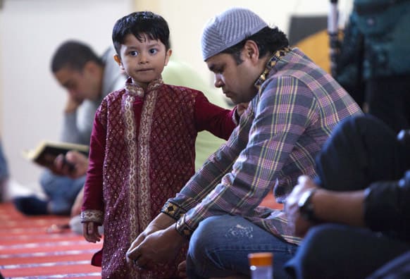 A boy stands next to his father during a prayer service at the Islamic Society of Boston mosque in Cambridge, Mass.