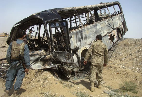 Afghan police and army soldiers inspect a burned bus after it collided with the wreckage of a truck that was attacked by Taliban insurgents in Maiwand district, on the highway between Kandahar and Helmand, Afghanistan. Scores of people aboard the bus were killed in the fiery crash.