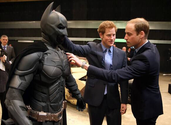 Britain`s Prince William and his brother Prince Harry look at a `Batsuit` used in the Batman films as they and Kate the Duchess of Cambridge attend the inauguration of
